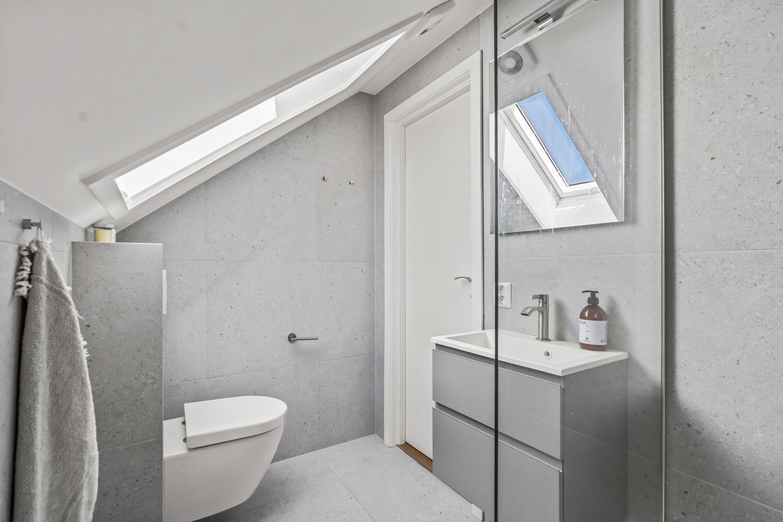 Badet har skuffeinnredning med nedfelt servant og speil med lys. Det er veggmontert toalett, samt dusjhjørne med dusjvegg. Fordelerskap er plassert bak servantskapet. På badet er det en elektrisk dampstyrt vifte som trekker ut luften, det er tilluft fra l Galleribilde
