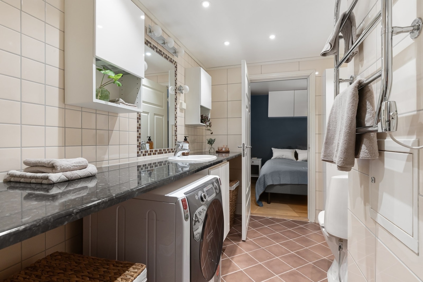 Badet har fliser på gulv med gulvvarme, fliser på vegger og malt himling med downlights Galleribilde