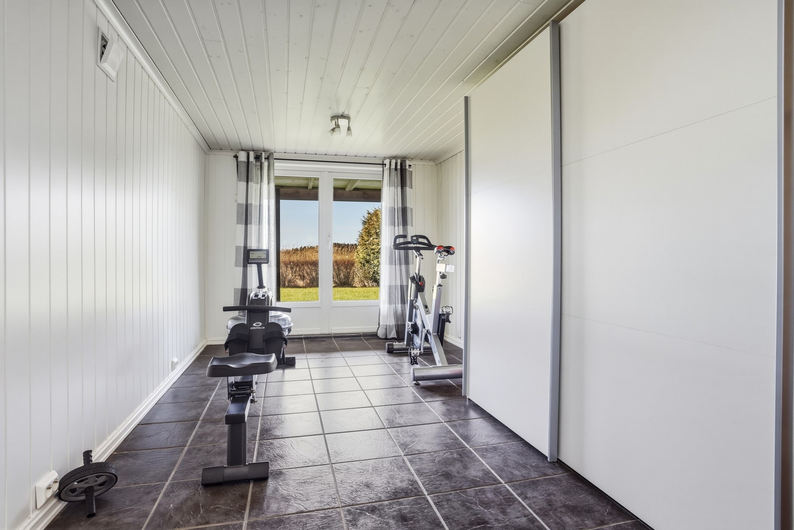Treningsrom med flislagt gulv og store vinduer som gir godt med naturlig lys. Galleribilde