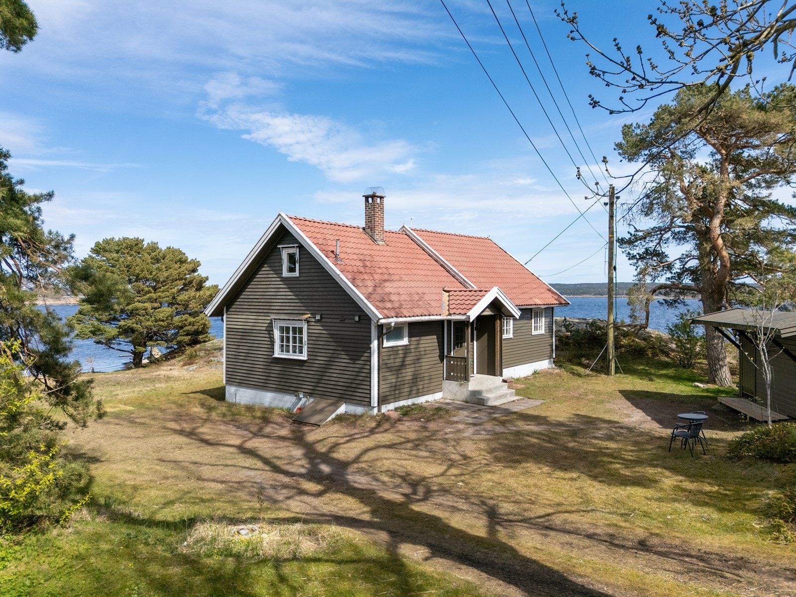 Eiendommen ligger på en naturtomt med plenarealer, svaberg og skogsvegetasjon Galleribilde