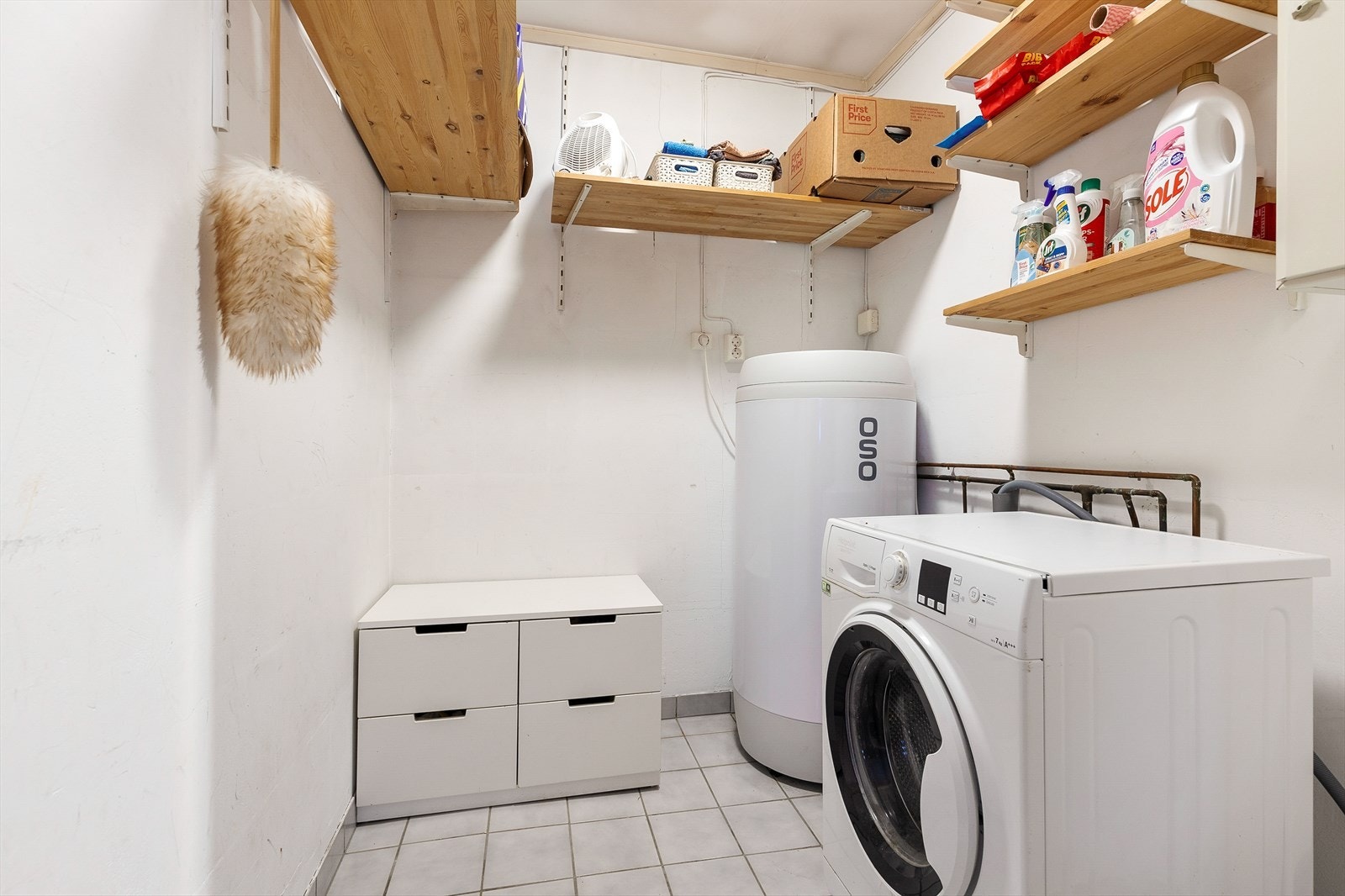 Vegg i vegg med badet er det separat vaskerom med flislagt gulv og gulvvarme. Ny varmtvannsbereder ble installert i 2023. Galleribilde