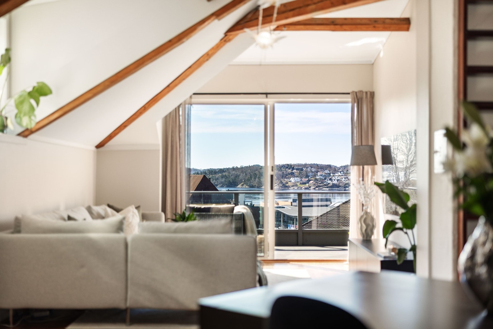 Romslig stue med store vinduer som gir mye lys og utsikt mot vann og nærliggende bebyggelse. Galleribilde