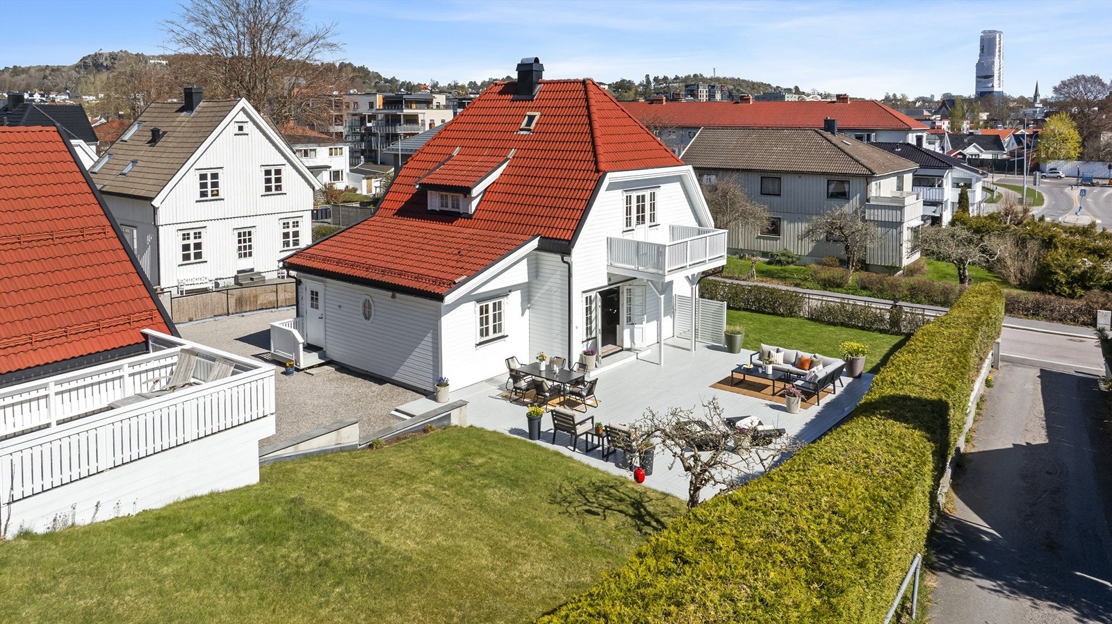 Et overblikk over den store, private hagen. Tomten er pent opparbeidet med en stor plen og en sjenerøs terrasse, skjermet av en tett hekk. Galleribilde