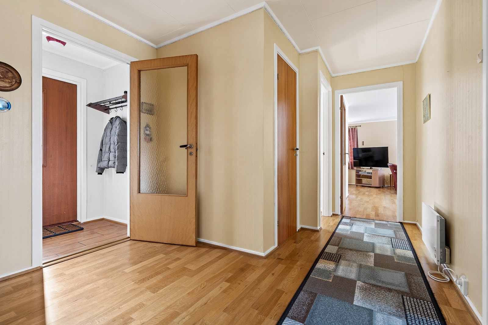 Gangen har parkett på gulvet og leder videre inn til stuen. Galleribilde