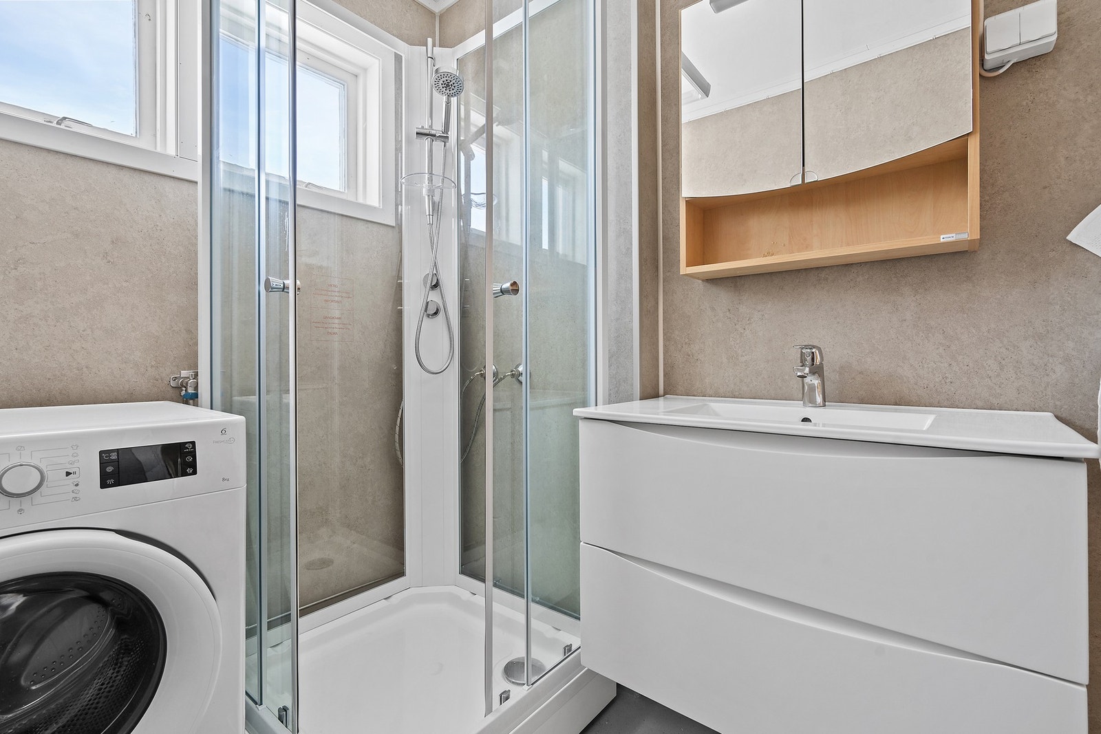 Badet er utstyrt med dusjkabinett, servantinnredning og har opplegg for vaskemaskin. Galleribilde