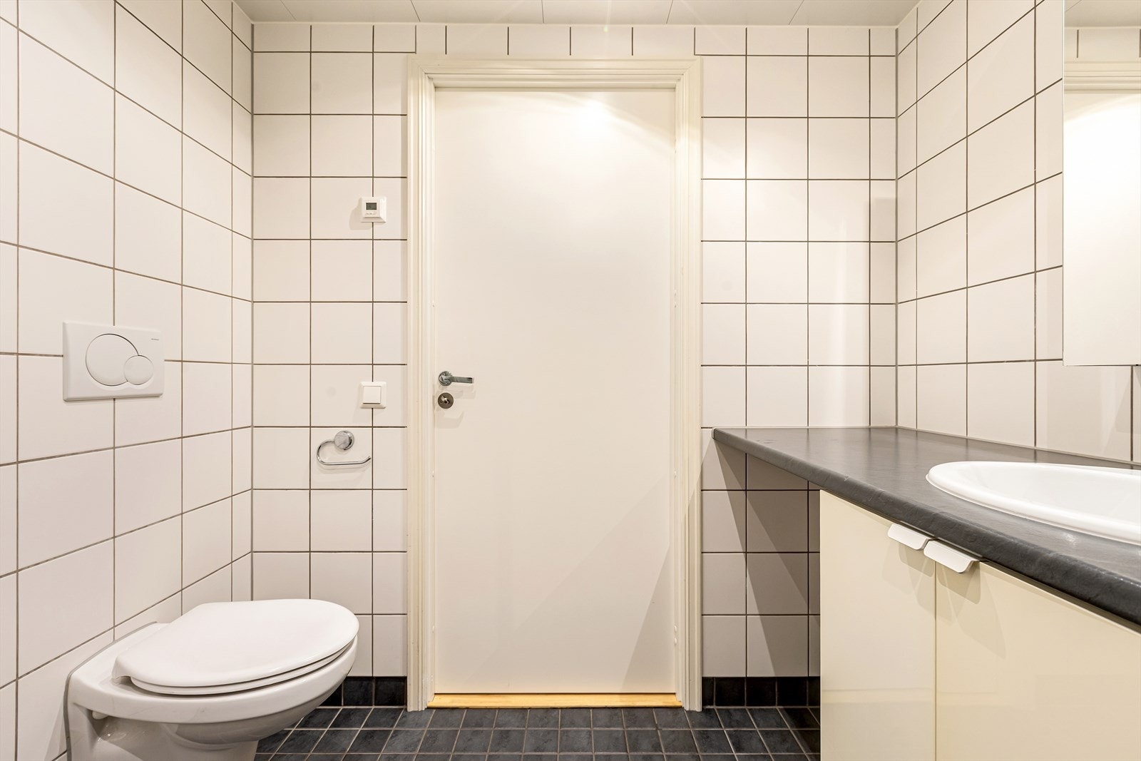 Badet har veggmontert toalett, flislagte overflater og balansert ventilasjon Galleribilde