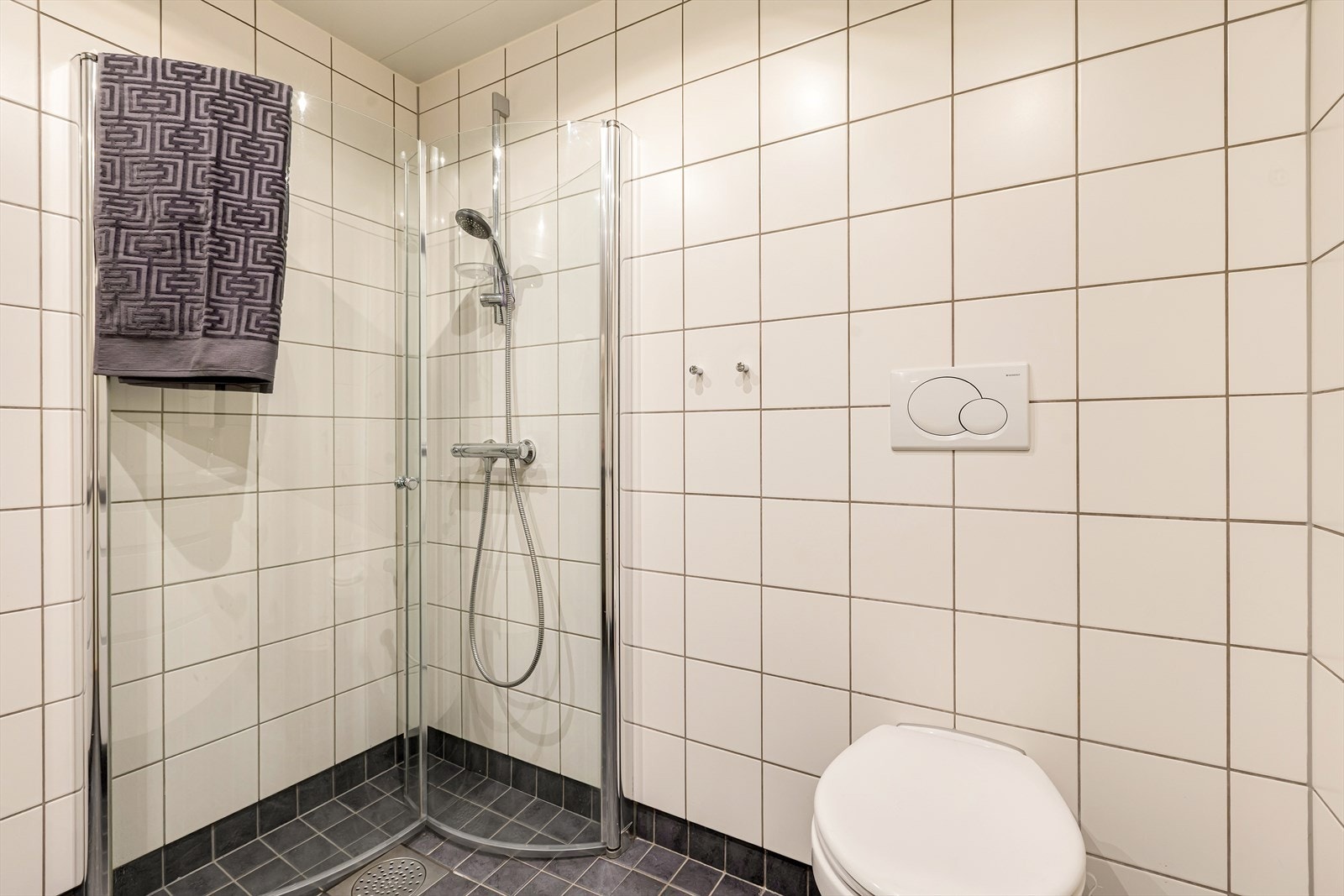 Dusjhjørne med glassvegg og sluk plassert i dusjsonen Galleribilde
