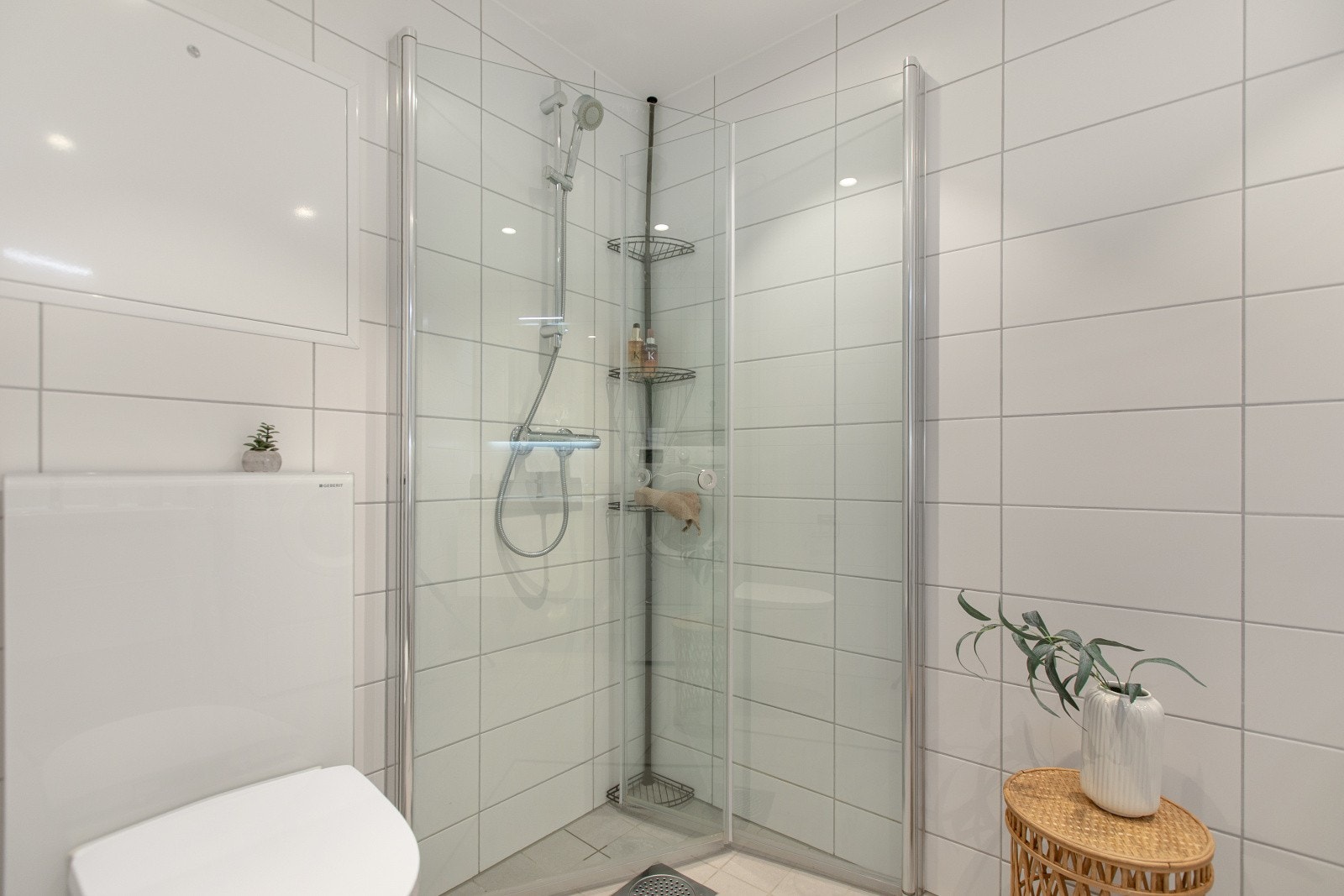 Badet er utstyrt med dusjnisje med innfellbare glassdører, vegghengt toalett og servantinnredning med tilhørende speil. Galleribilde