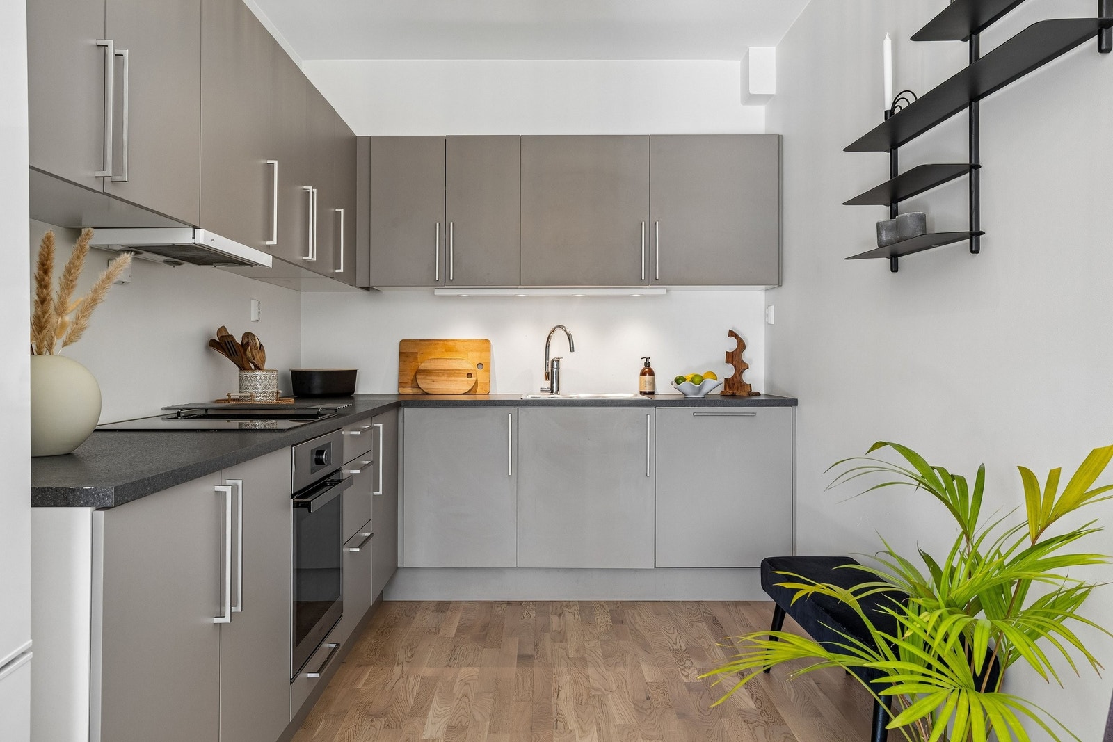 Moderne Sigdal kjøkken med tilhørende hvitevarer. Det er godt med benkeplass på kjøkkenet. Mørk/grå benkeplate i laminat og ventilator med komfyrvakt. Galleribilde