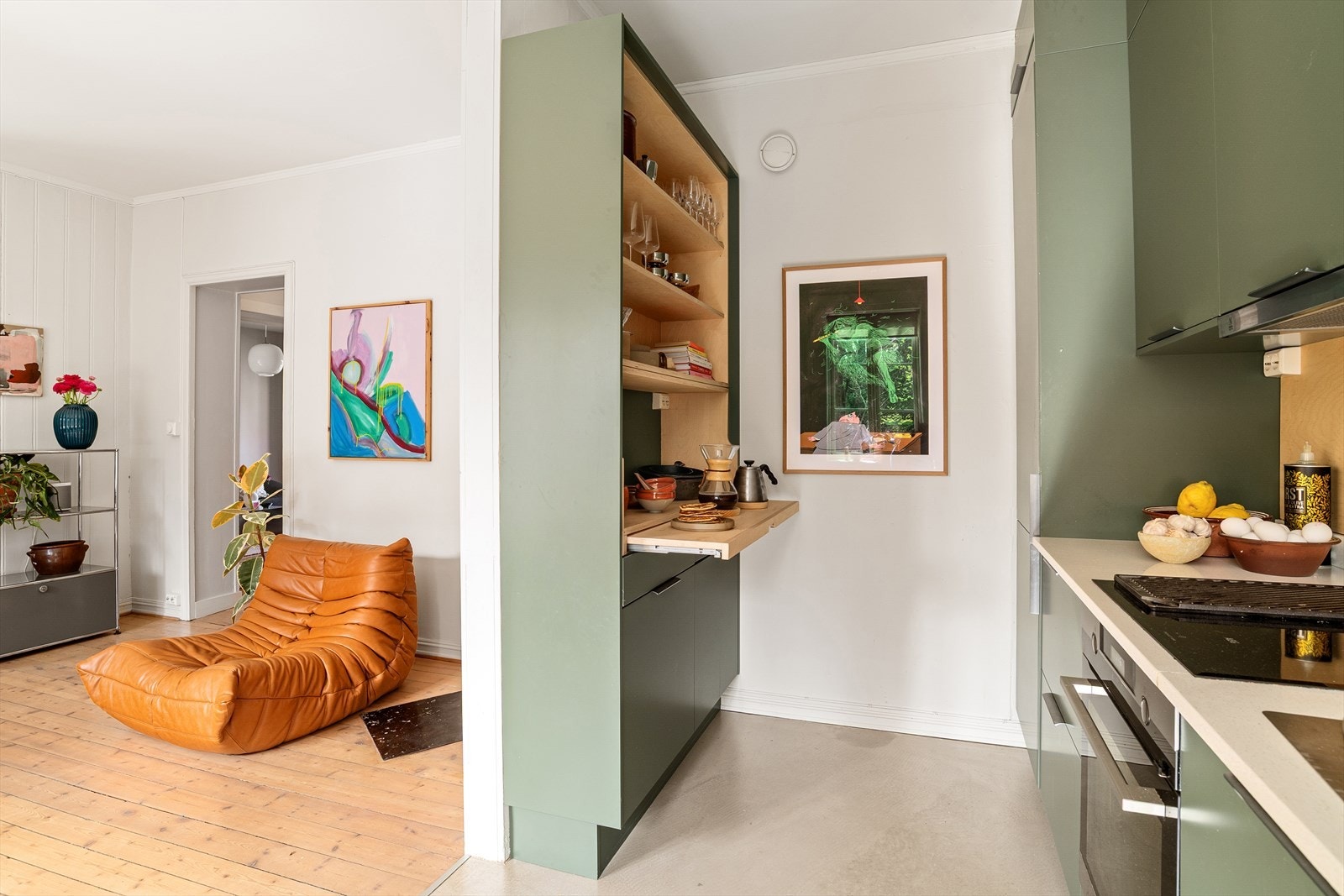 En halvvegg på kjøkkenet skaper et behagelig skille og gir rom for ekstra skap- og hylleplass. Den uttrekkbare hyllen på halvveggen er perfekt når man trenger ekstra benkeplass. Galleribilde