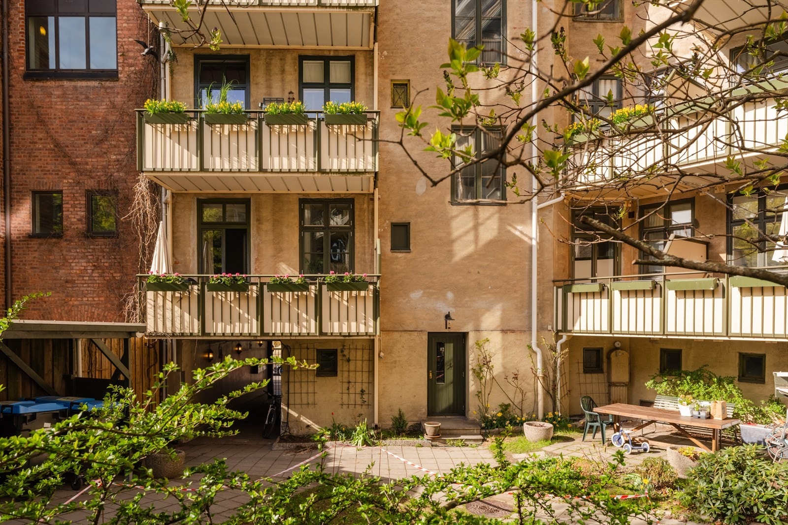 Bakgården byr på et frodig og velstelt uteområde med gressplen, vakre beplantninger og hyggelige sitteplasser. Galleribilde
