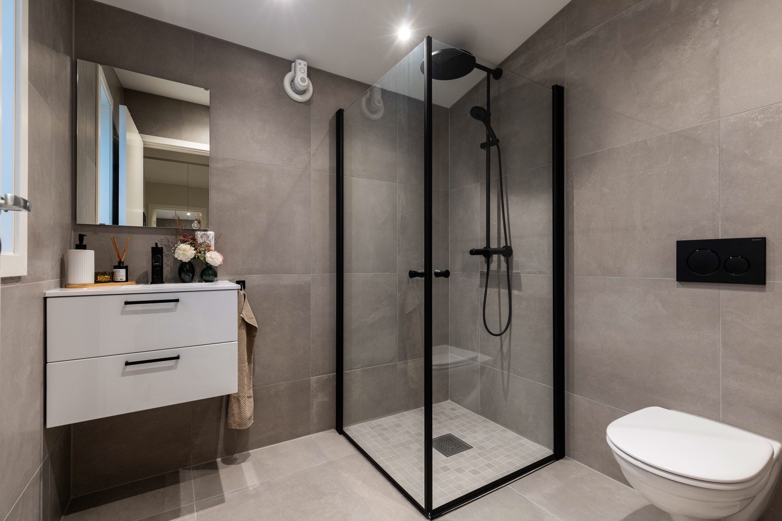 Badet i første etasje fremstår som moderne og delikat, med store 60x60-fliser og downlights i himlingen Galleribilde