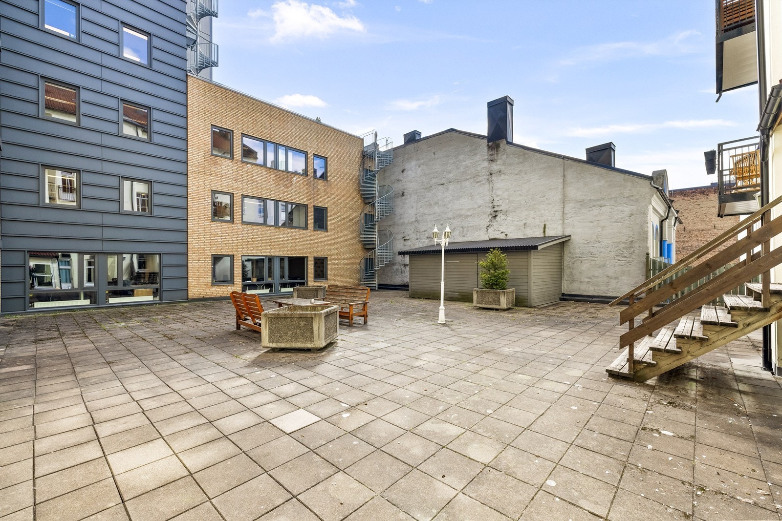 Felles, hellebelagt bakgård med sittegrupper og sykkelbod. Galleribilde