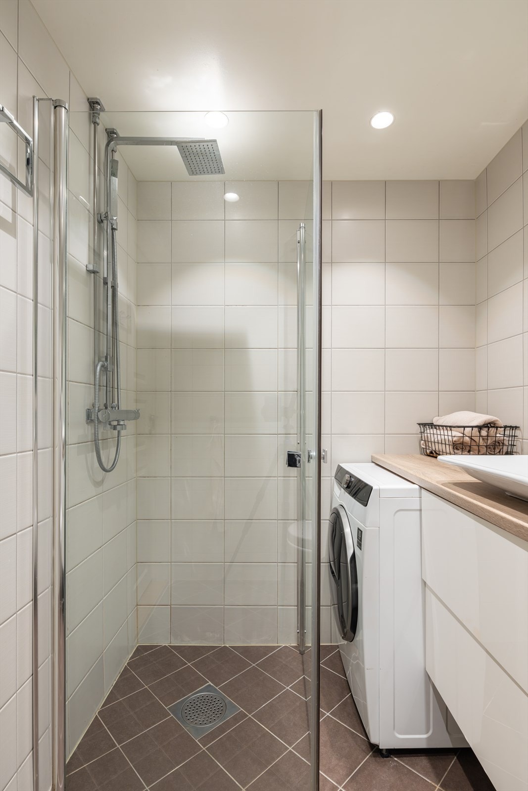 Badet er innredet med vegghengt toalett, servant med underskap og dusjhjørne med svingbare glassdører. Det er opplegg for vaskemaskin. Galleribilde
