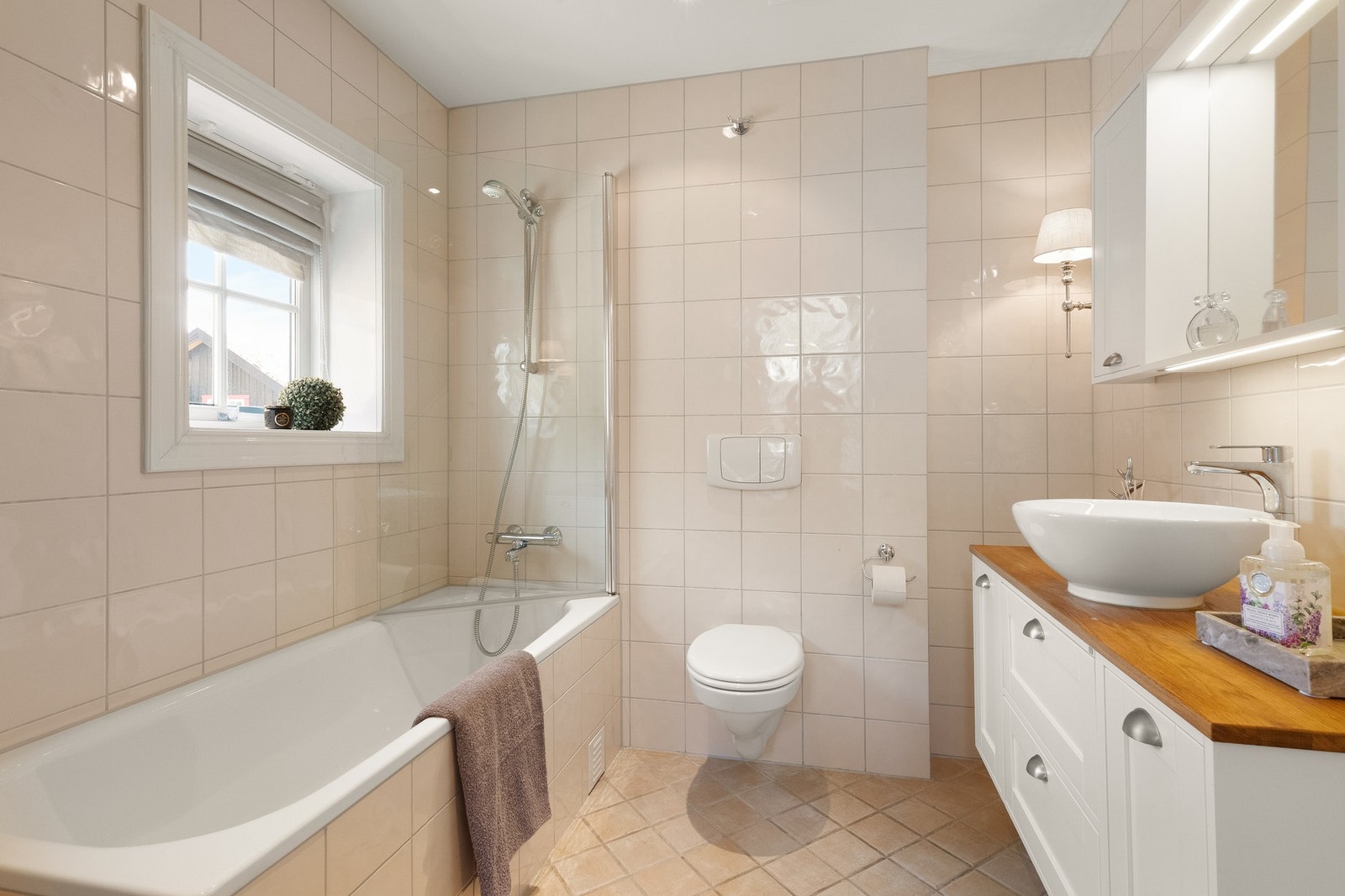 Pent, flislagt bad med varmekabler og downlights, innredet med servantseksjon og innfliset badekar. Galleribilde