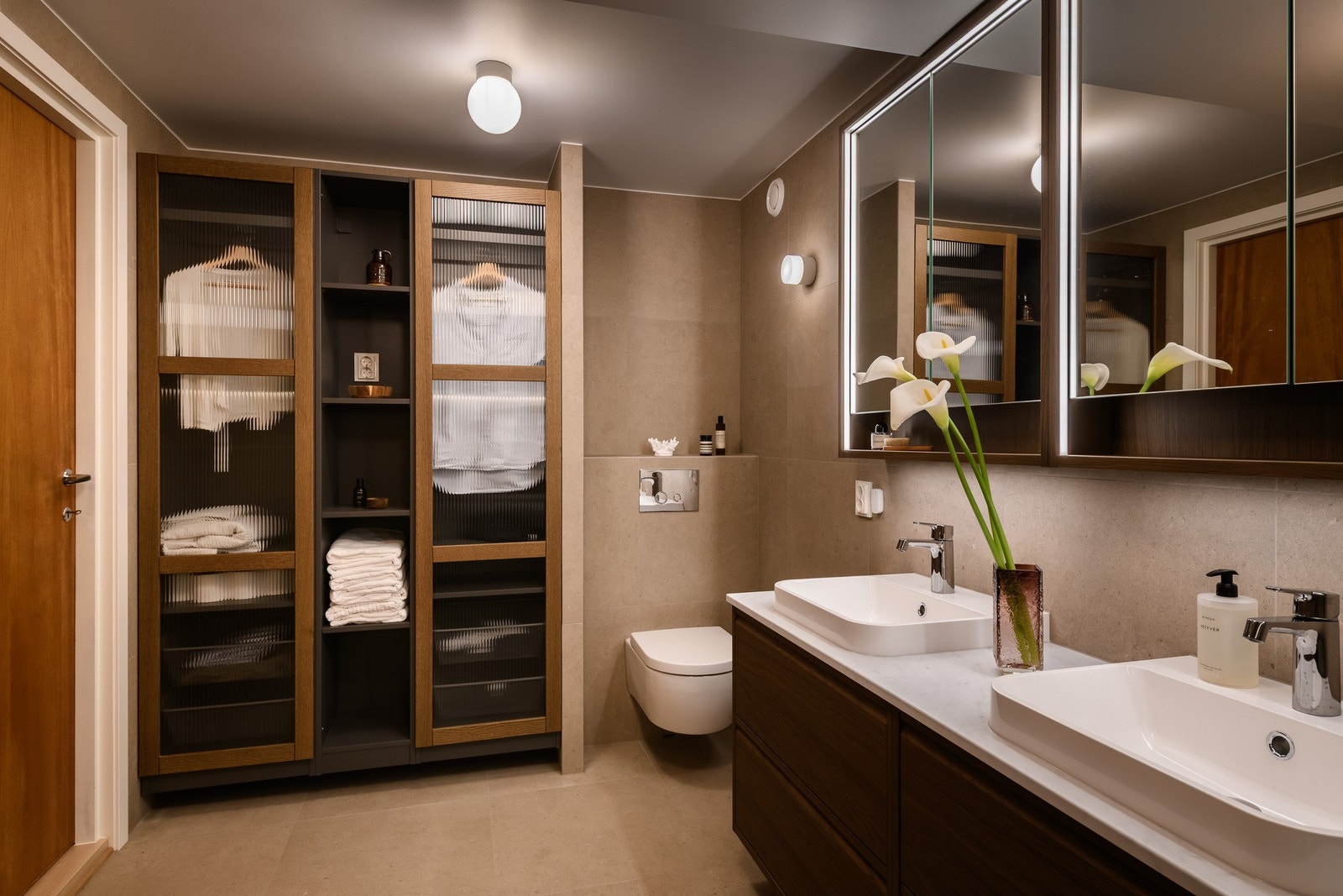 Badet har rikelig med oppbevaring i både speilskap og et eget garderobeskap med glassdører. Galleribilde