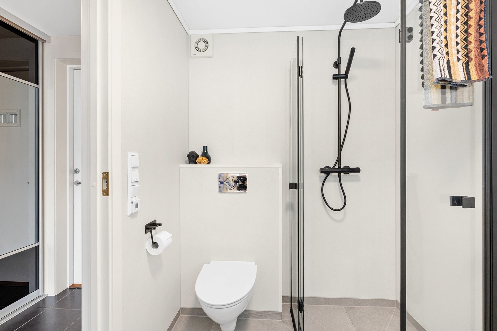 Badet er innredet med servant i baderomsmøbel, vegghengt toalett og dusjshjørne med glassdører, og har opplegg til vaskemaskin. Galleribilde