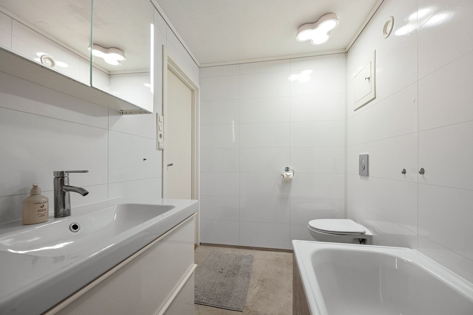Badet er innredet med et vegghengt toalett, badekar med vegghengt dusj og servant. Galleribilde