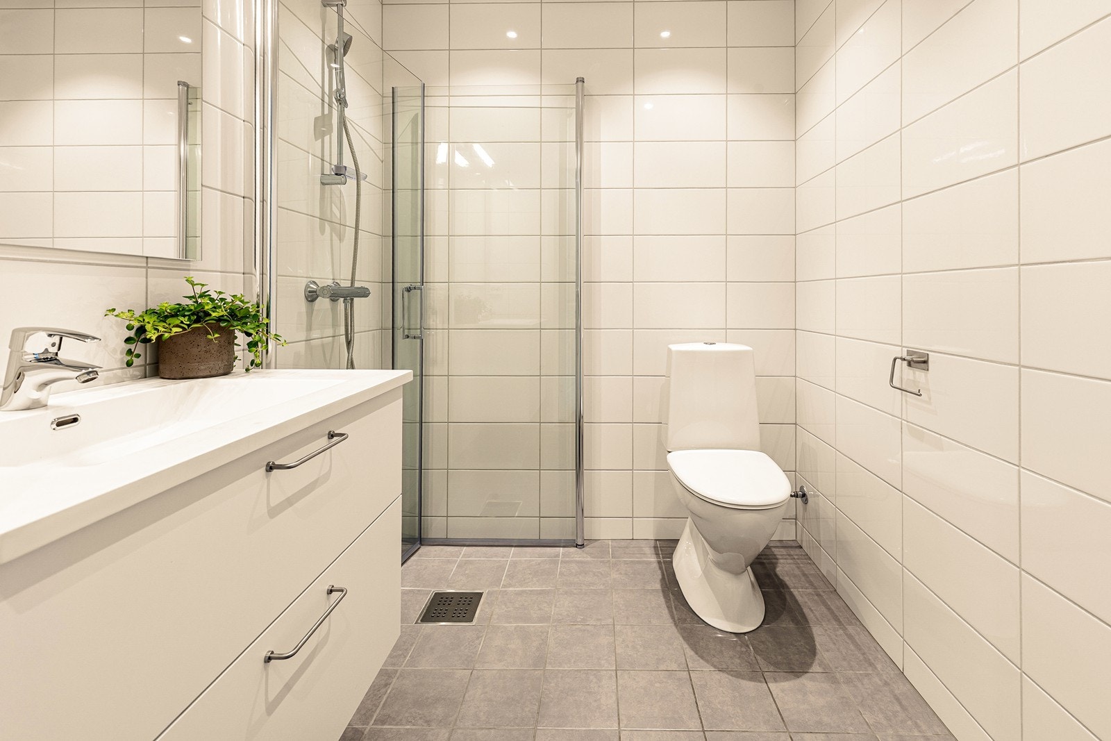 Badet i første etasje har flislagte gulv med varmekabler, vegger med 20x40 flis, og praktiske innfellbare dusjdører. Galleribilde