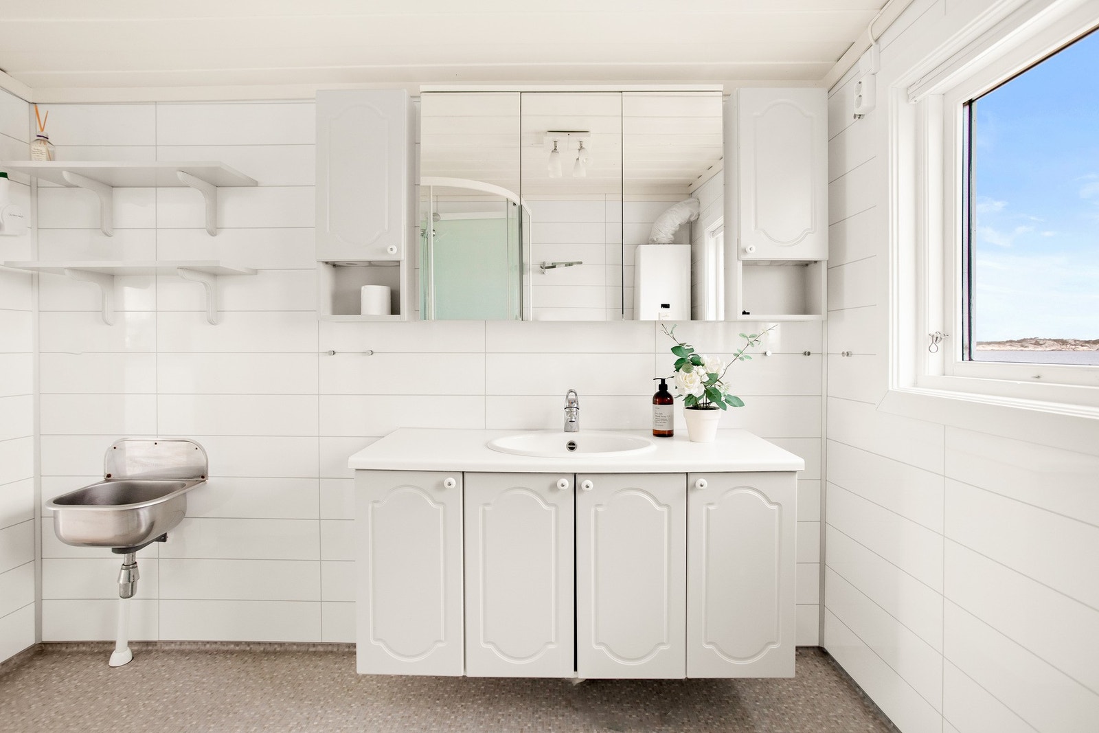 Badet er enkelt utformet og har servant med vask, og dusjkabinett. Galleribilde