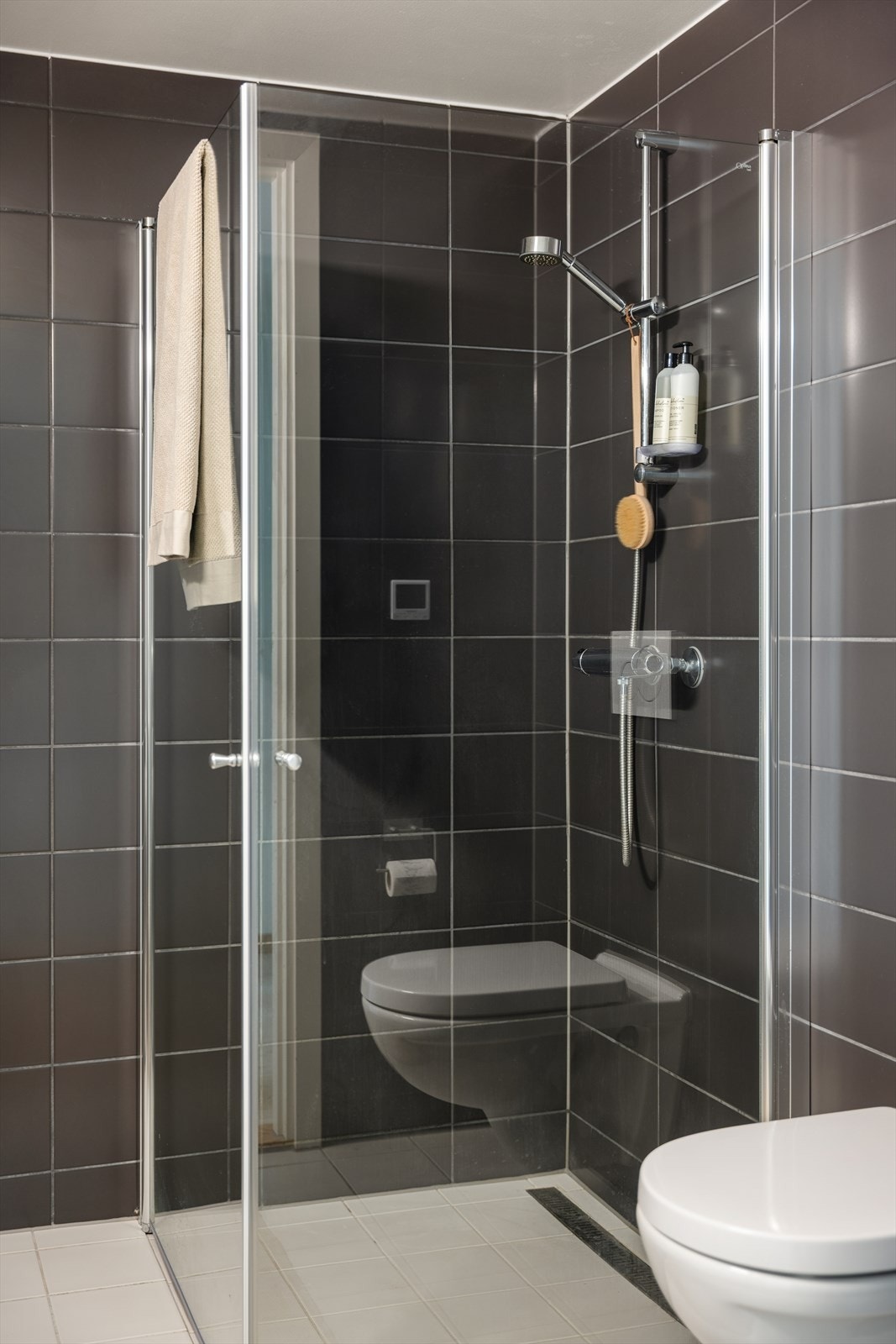 Baderomsinnredningen består av servant med underskap, speil med overlys, vegghengt klosett, dusjhjørne med svingbare glassdører og opplegg for vaskemaskin. Galleribilde