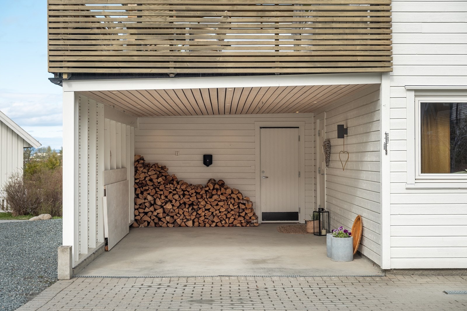 På eiendommen er det gode parkeringsmuligheter i både carport og flere biloppstillingsplasser. Det ble lagt duk og utvendig kledning i taket i 2022, samt innlagt elbillader i carporten og spotter i taket. Galleribilde