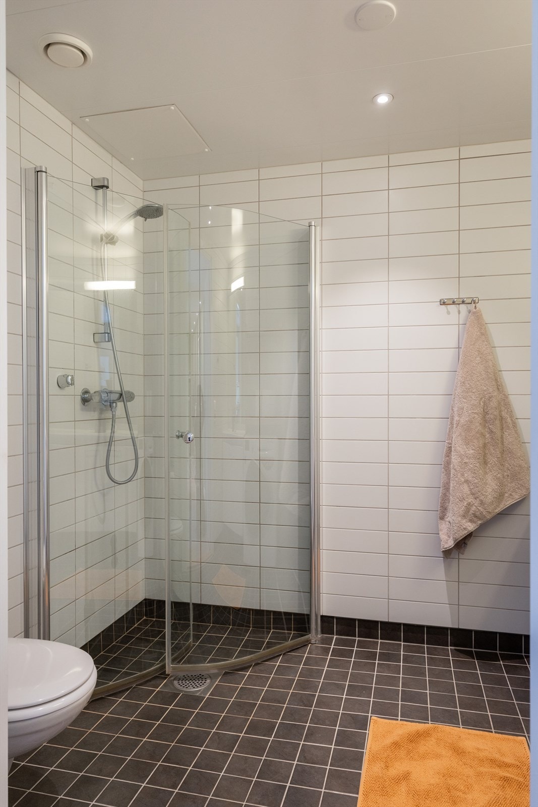 Badet er innredet med servant med underskap, speil, belysning, toalett og en praktisk dusjsone med innfellbare dusjdører. Galleribilde