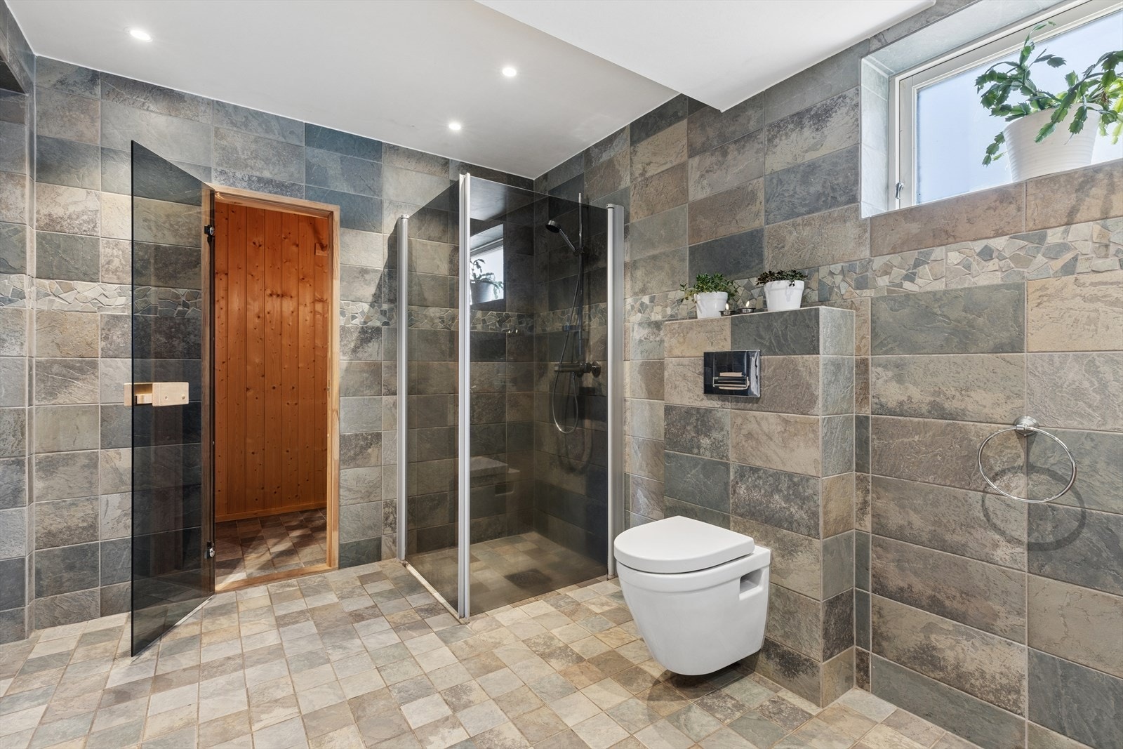 Fra badet er det direkte inngang til en badstue med glassdør og Helo badstuovn Galleribilde