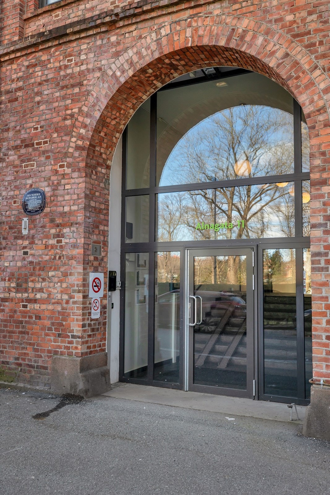 Hovedinngangen er markert med en buet teglsteinsportal og glassdører. Galleribilde