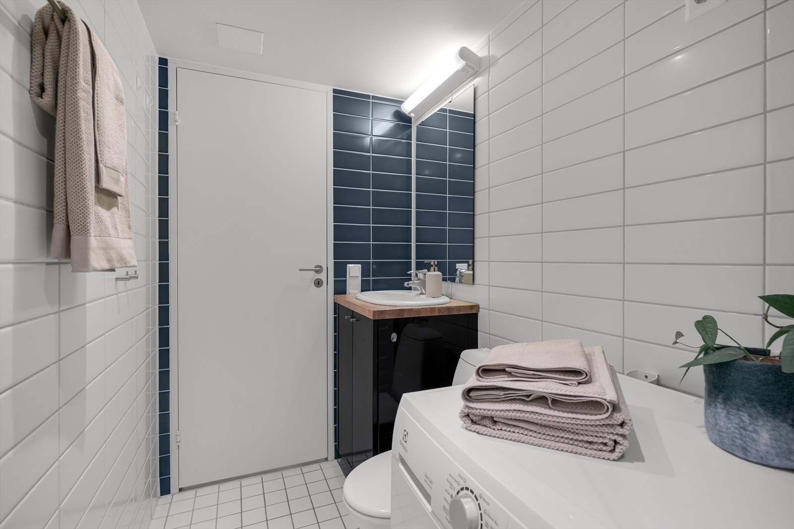 Badet er utstyrt med veggmonterte dusjdører, wc og opplegg for vaskemaskin. Galleribilde