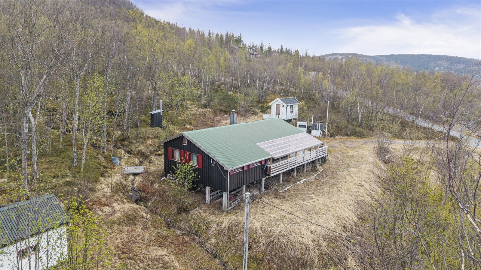 Hytta ligger på en hellende naturtomt med gruset oppkjørsel. Galleribilde