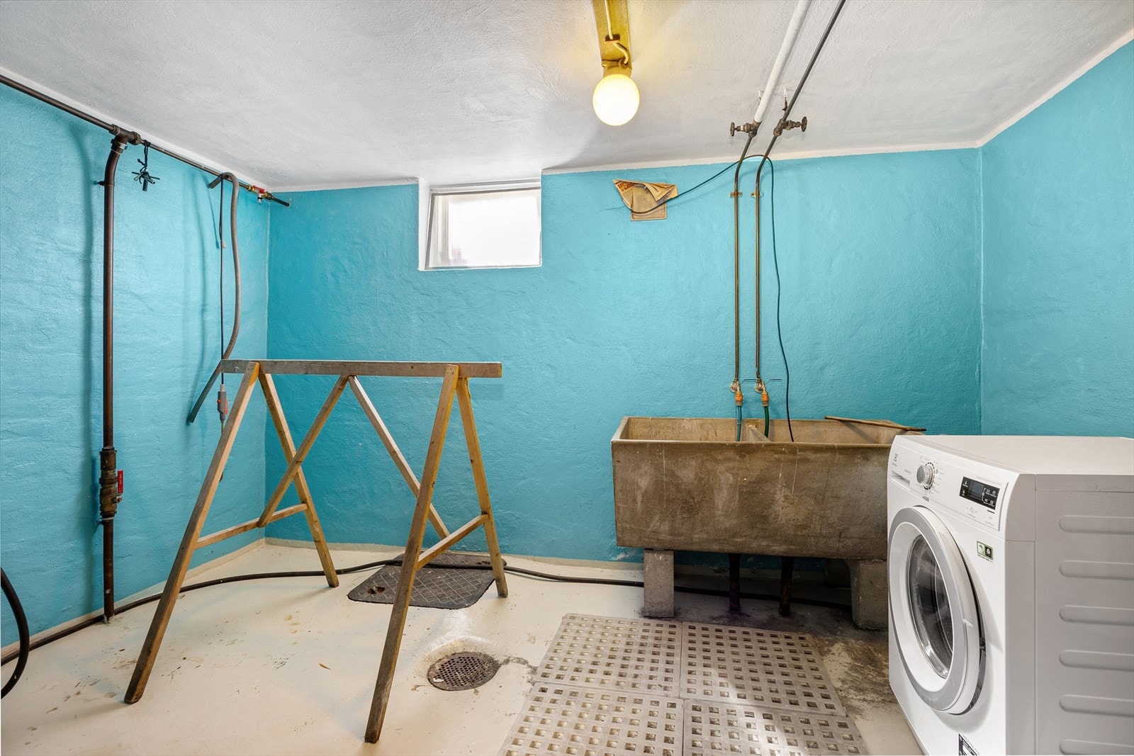 Praktisk vaskerom i kjelleren med skyllekar i betong og opplegg for vaskemaskin. Galleribilde
