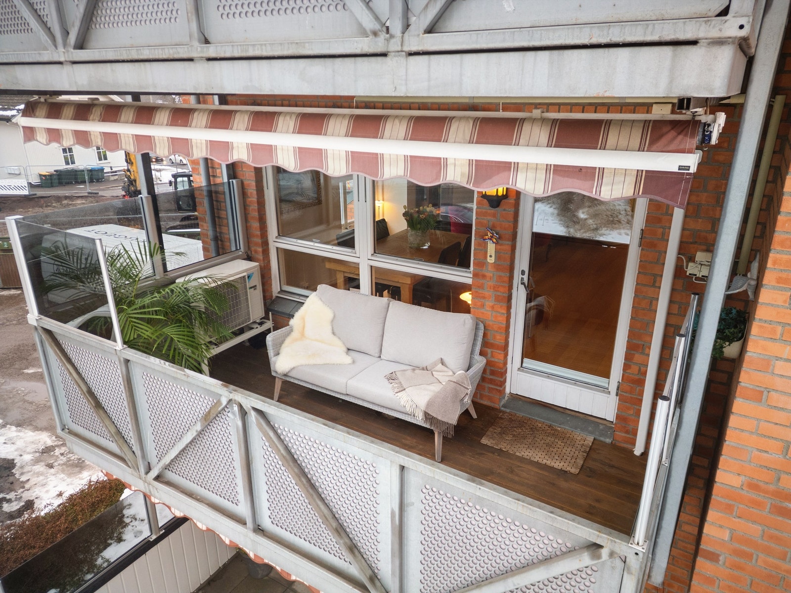 Balkongen er utstyrt med levegger av glass på rekkverk, utvendig belysning, strømuttak, markise, terrassevarmer og terrassebord på gulv. Galleribilde