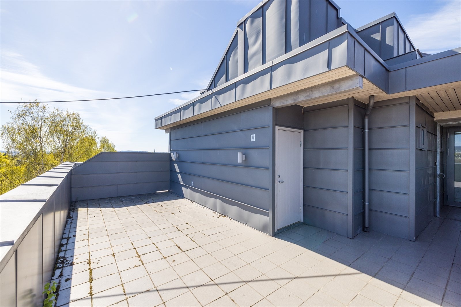 Felles takterrasse på øvre nivå med hellelagt dekke, levegg og plass til sittegruppe Galleribilde