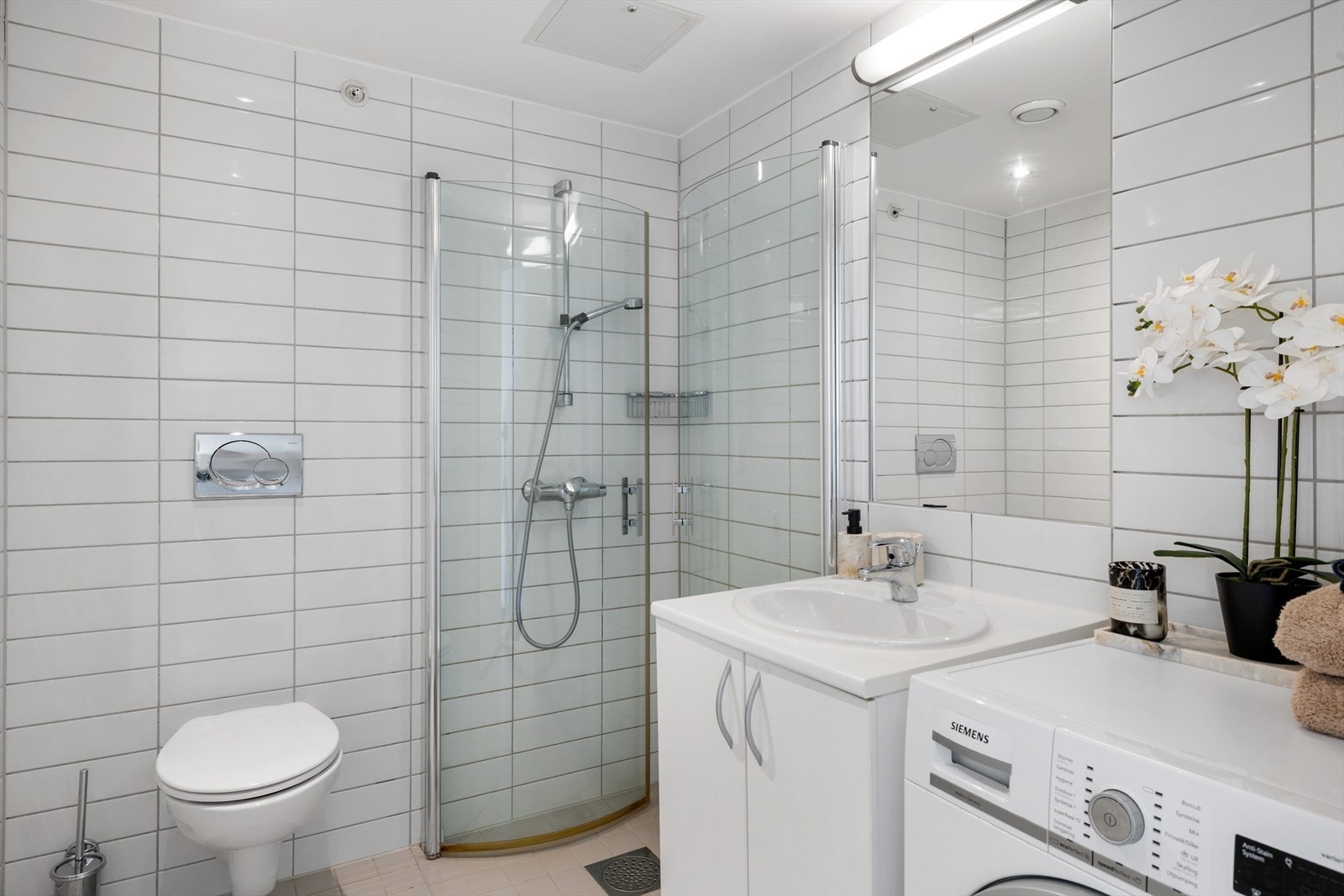 Badet har dusjhjørne, flislagte overflater og målt fall mot sluk Galleribilde