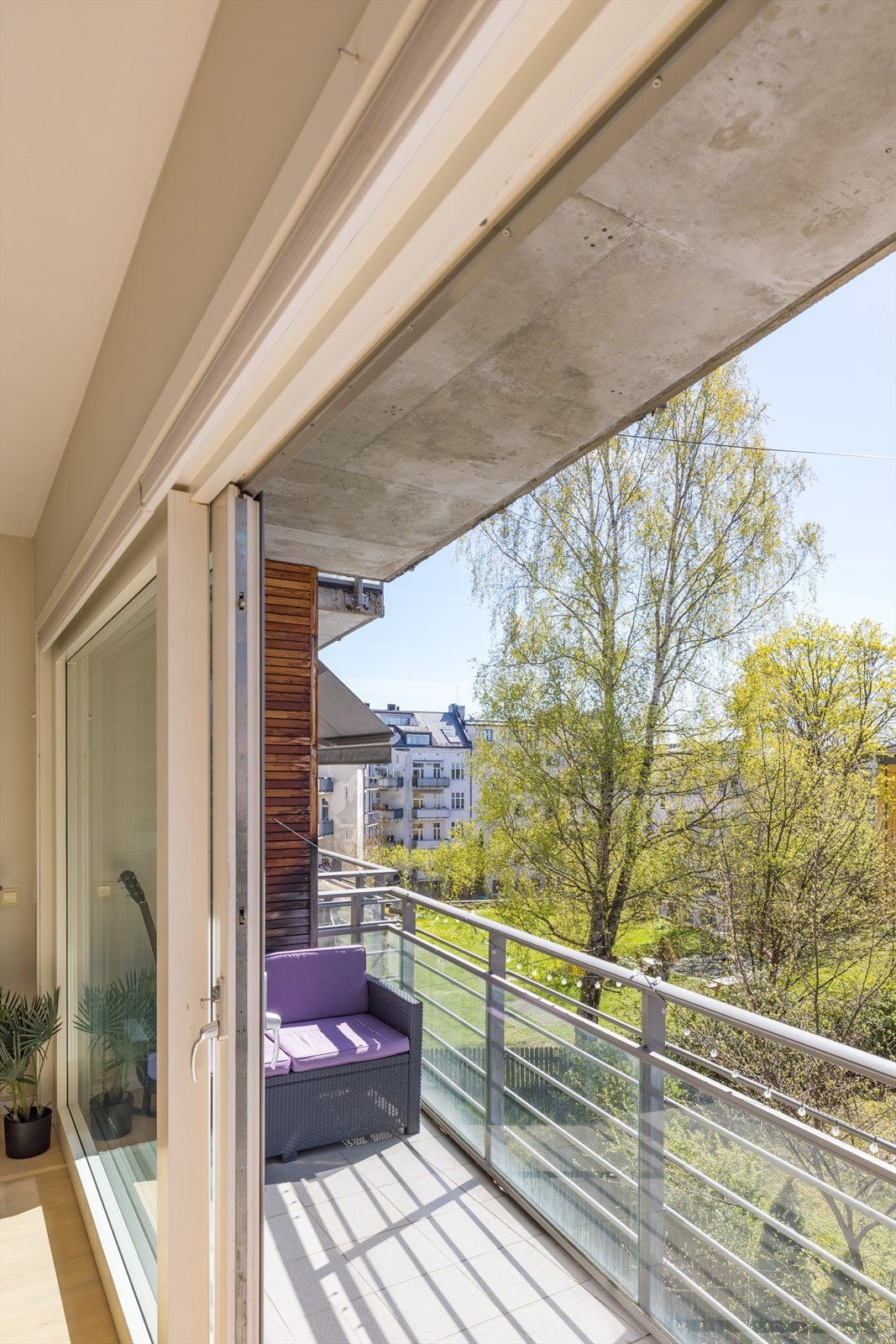 Overbygget uteparti med glassrekkverk og grønne omgivelser tett på bygget Galleribilde