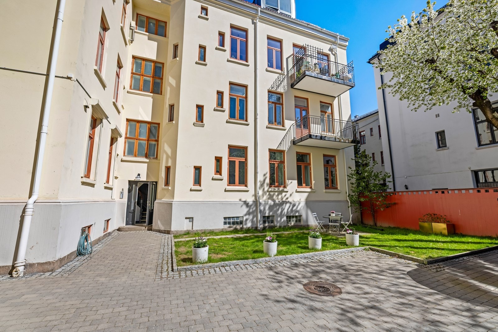 Felles gårdsrom med plen og brosteinsbelagte gangveier gir en sosial og funksjonell uteplass. Galleribilde