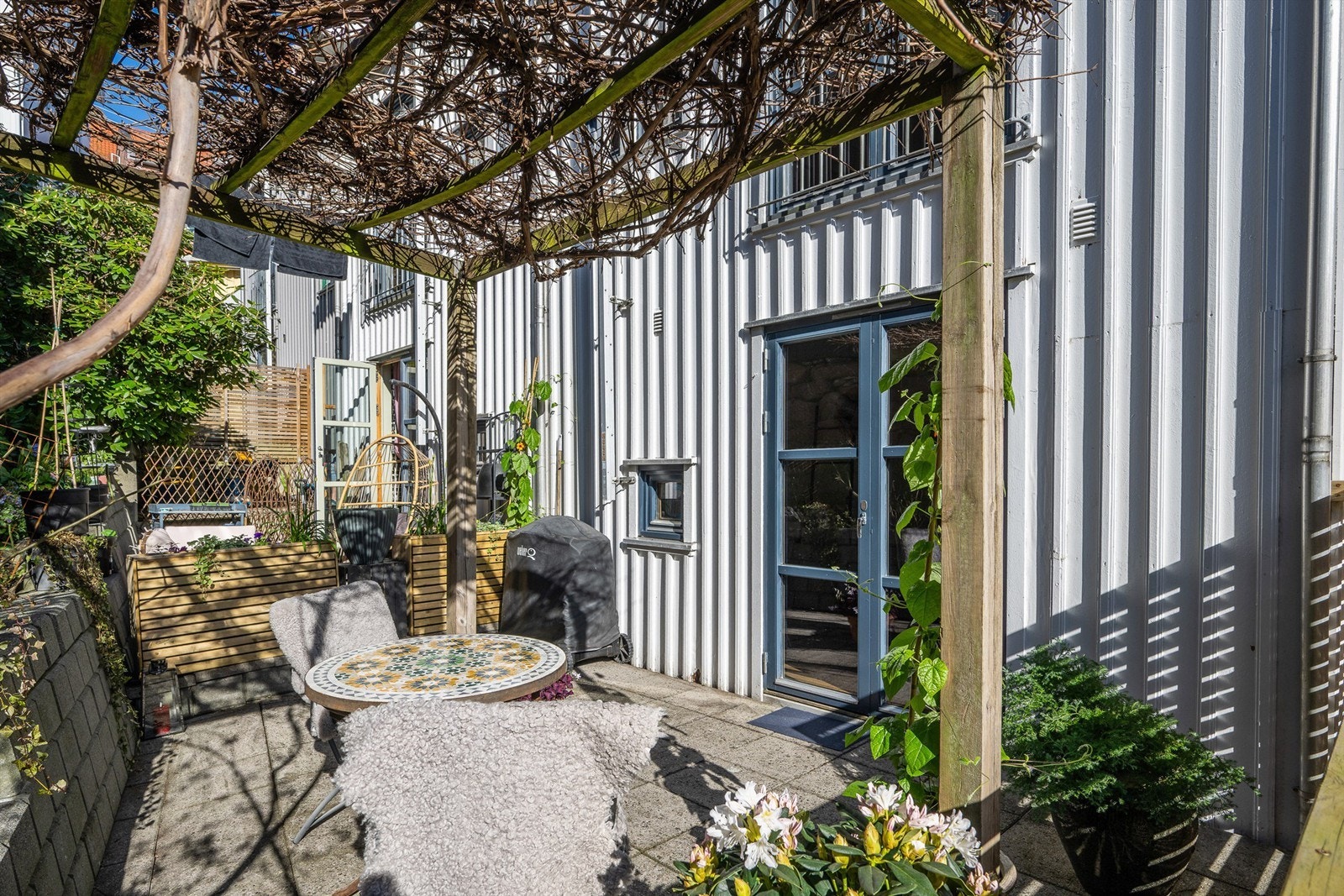 Et innholdsrikt rekkehus over tre plan, med to private uteplasser. Her er den skjermede markterrassen med adkomst fra første etasje. Galleribilde