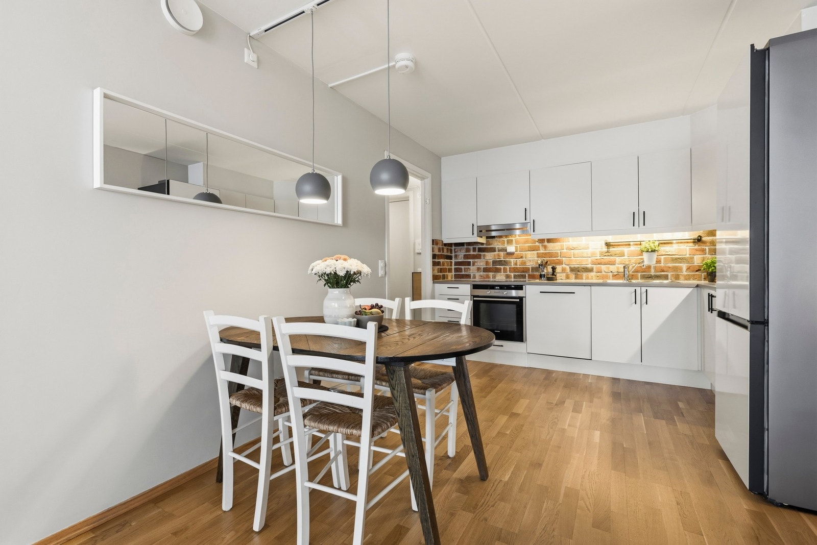 Åpen kjøkkenløsning i stue med takhøy innredning fra byggeåret, med glatte, folierte fronter. Galleribilde