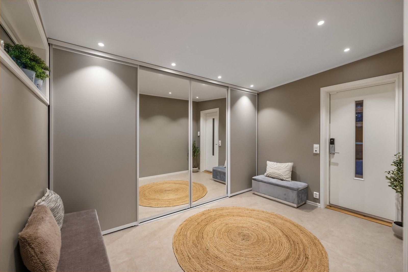 En romslig og innbydende entré med en stor skyvedørsgarderobe. Det er flislagte gulvflater med varmekabler. Galleribilde