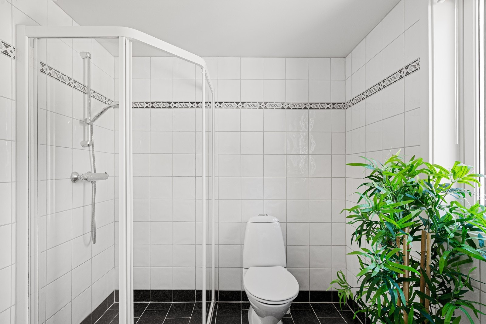 Badet er innredet med servant i underskap med speil over, toalett og dusjhjørne. Galleribilde