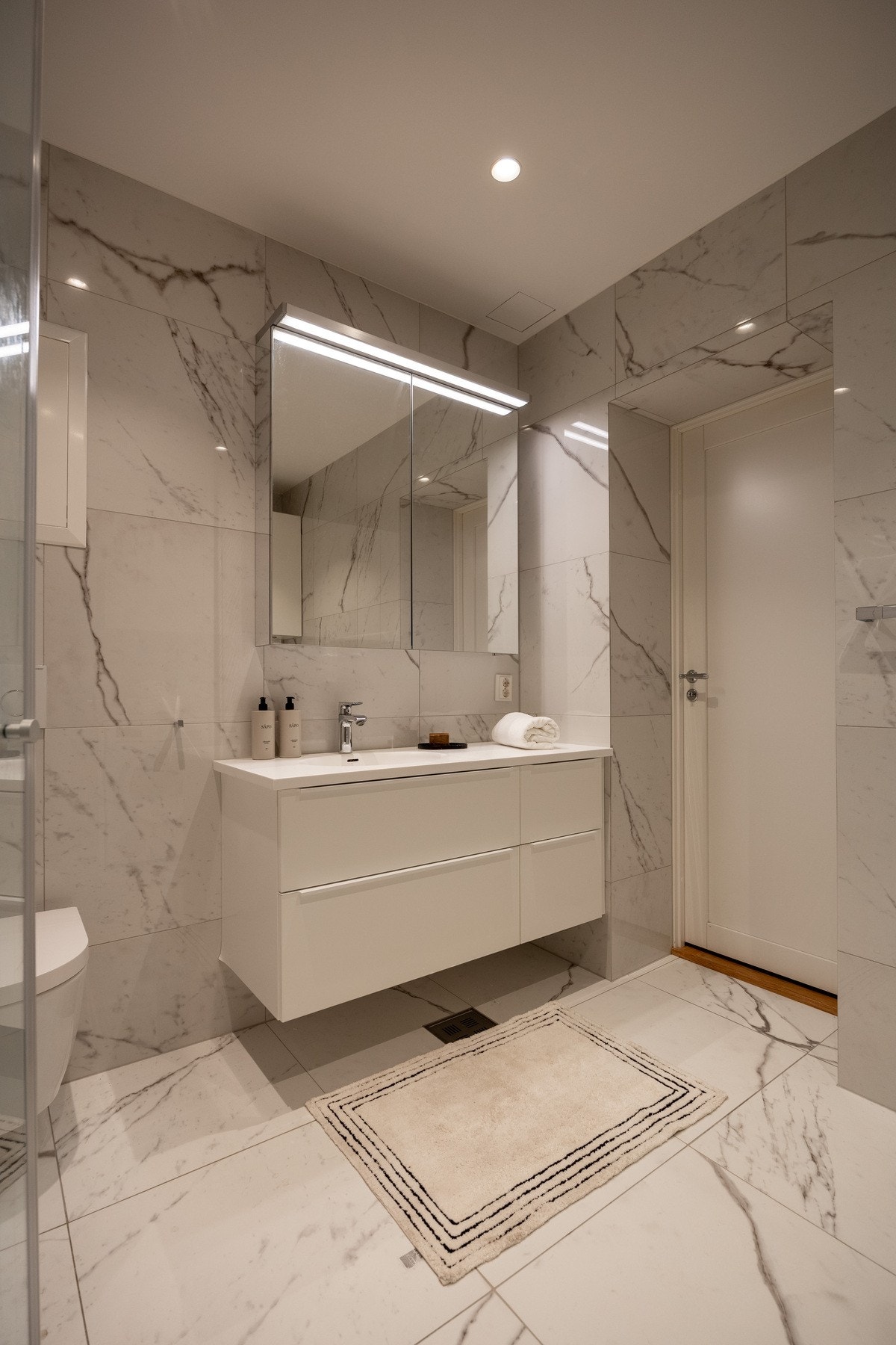 Badet er innredet med vegghengt skapinnredning, nedfelt servant, speilskap med lys, veggmontert toalett, samt dusjhjørne. Galleribilde