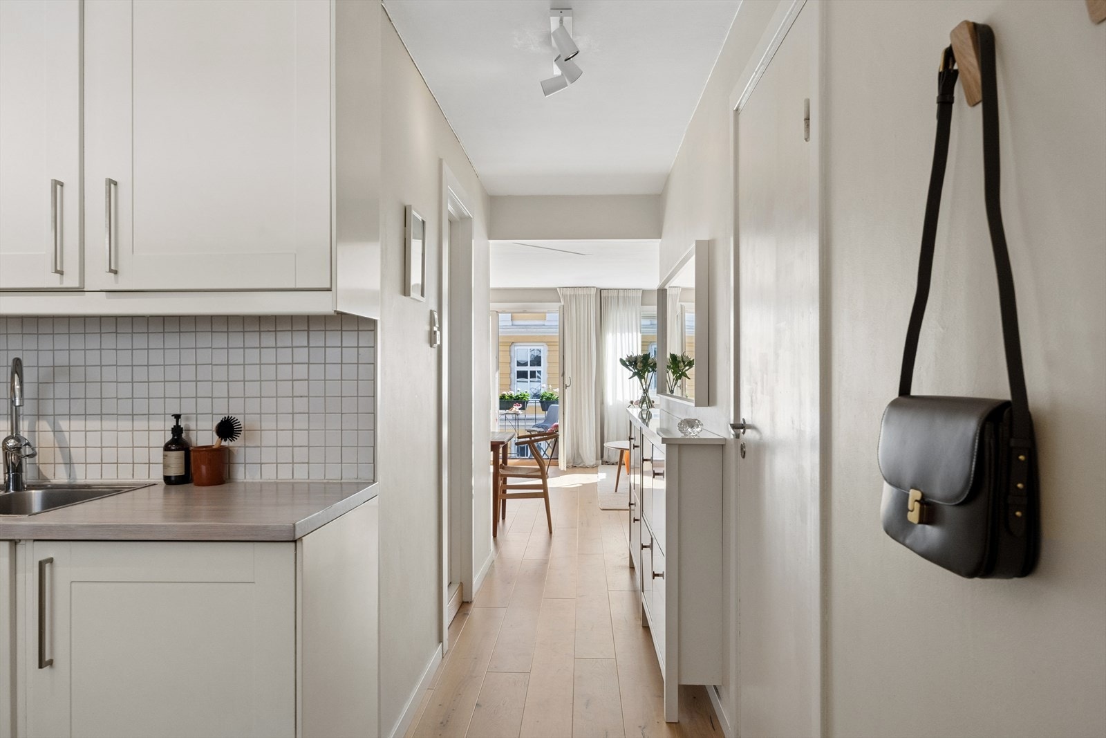 Entréen fungerer som et naturlig knutepunkt i leiligheten, hvor lyset fra de store vindusflatene i stuen slipper rikelig inn og bidrar til en lys og luftig atmosfære gjennom hele boligen. Galleribilde