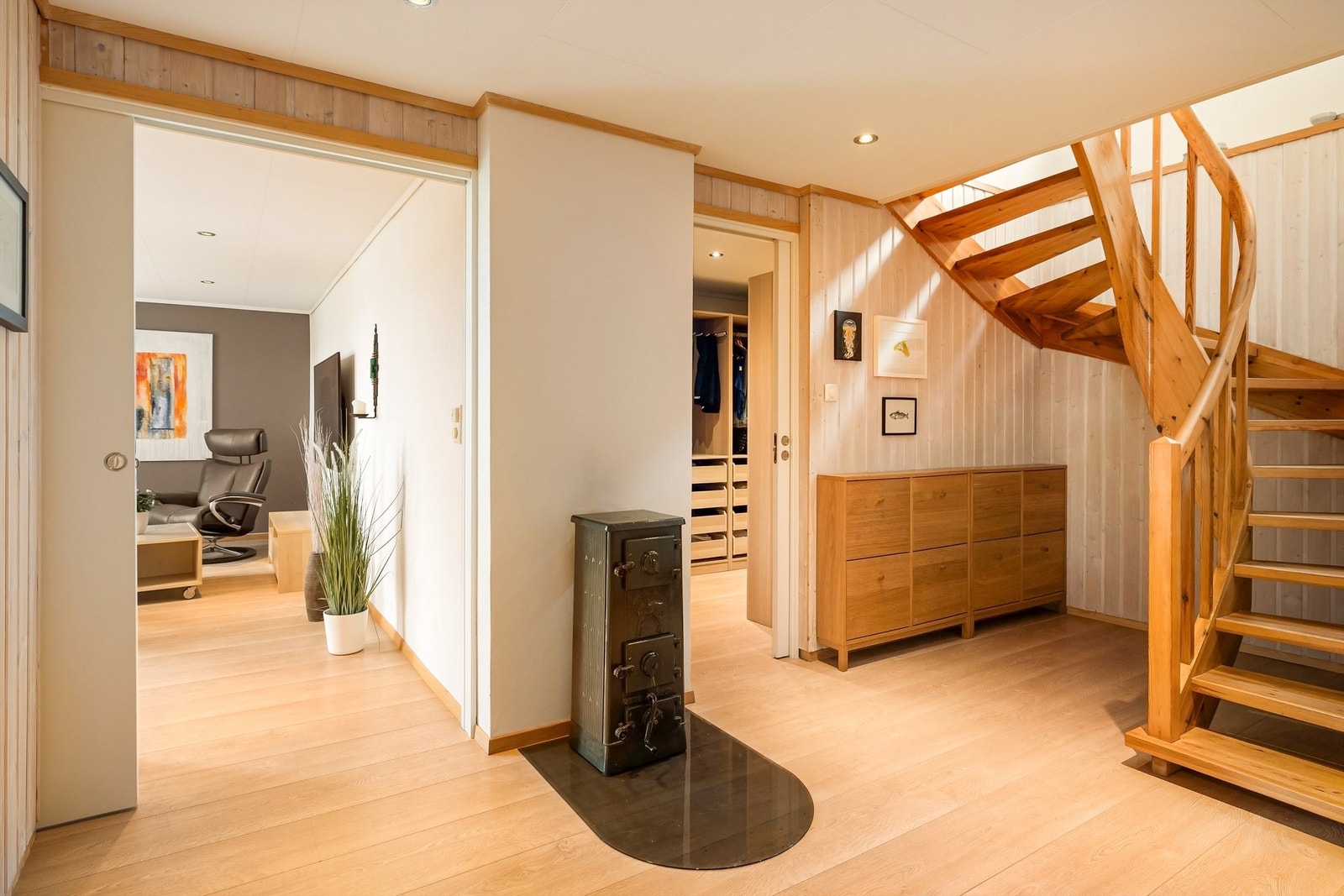 Fra hallen i første etasje er det tilgang til TV-stue og garderobe. Den lakkerte tretrappen leder opp til hovedetasjen. Galleribilde