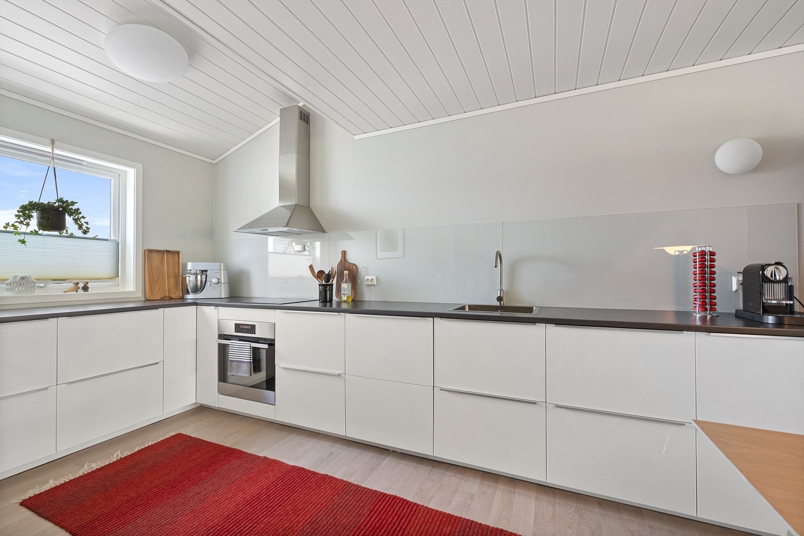 Kjøkkeninnredning med glatte, hvite fronter, laminat benkeplate og integrert stekeovn. Galleribilde