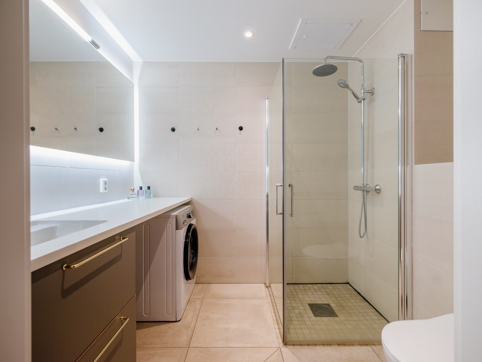Delikat og moderne bad med flislagte overflater og downlights i taket. Galleribilde