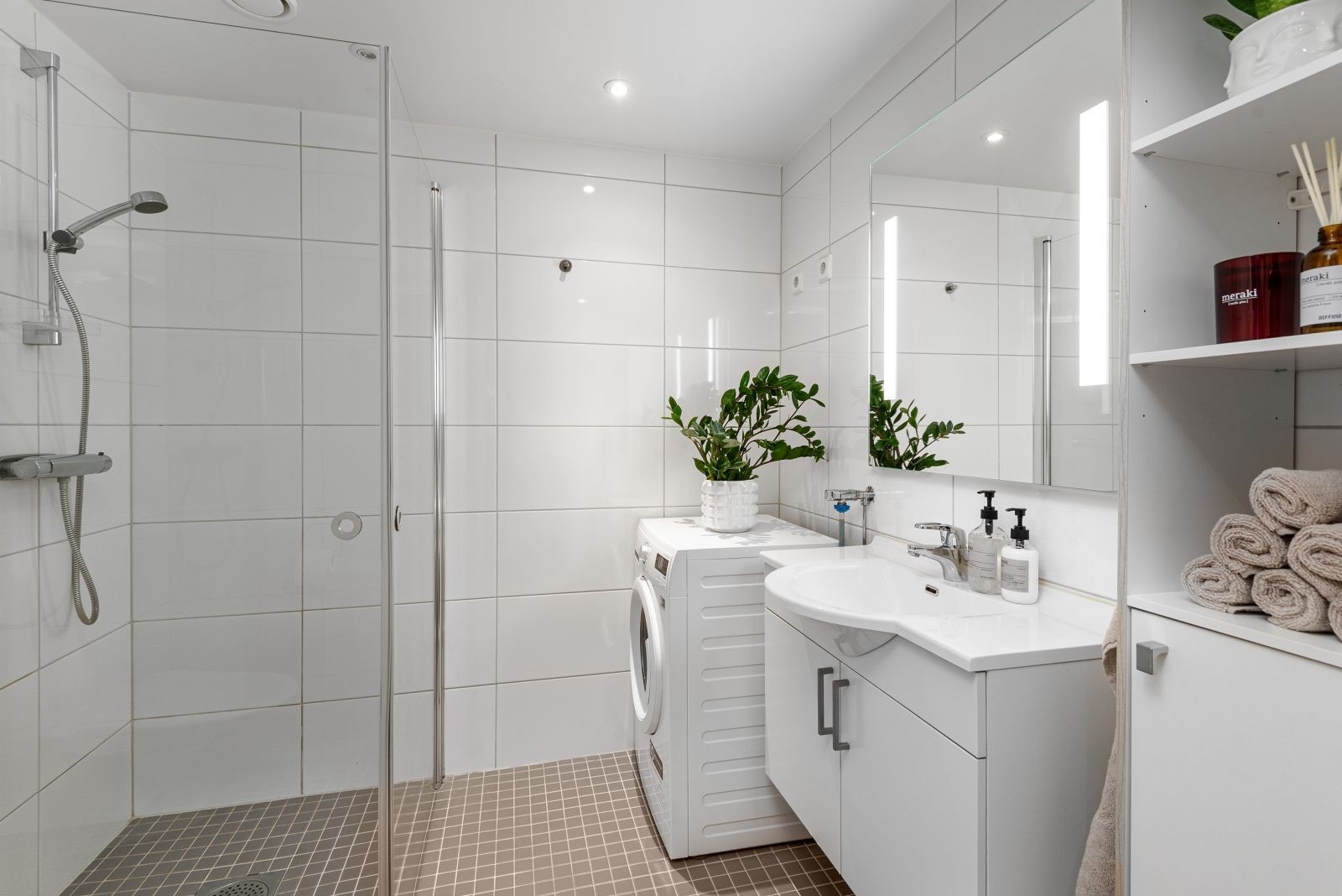 Badet er innredet innfellbare dusjdører, opplegg for vaskemaskin og vegghengt toalett. Galleribilde