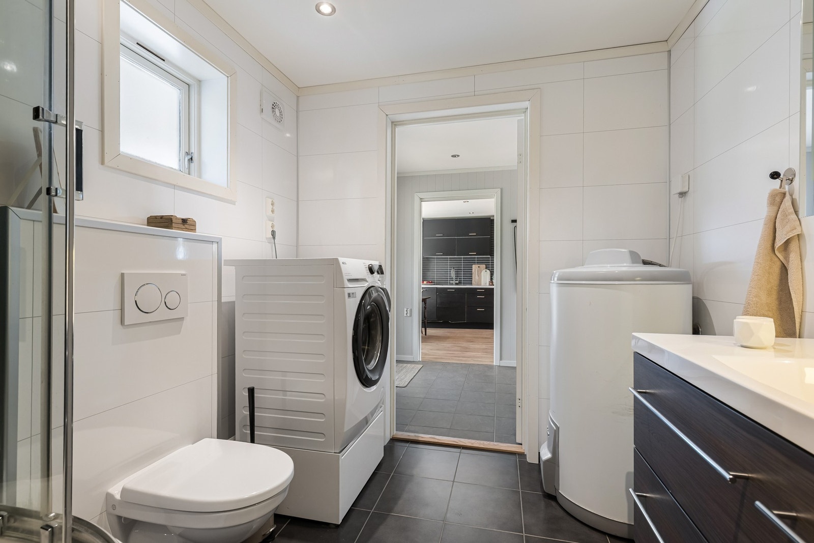 Badet er innredet med servantskap med heldekkende servant, veggspeil med lys, dusjkabinett og vegghengt toalett. Galleribilde