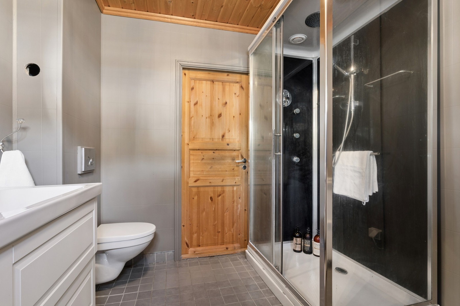 Badet er utstyrt med dusjløsning, toalett og servantinnredning. Galleribilde