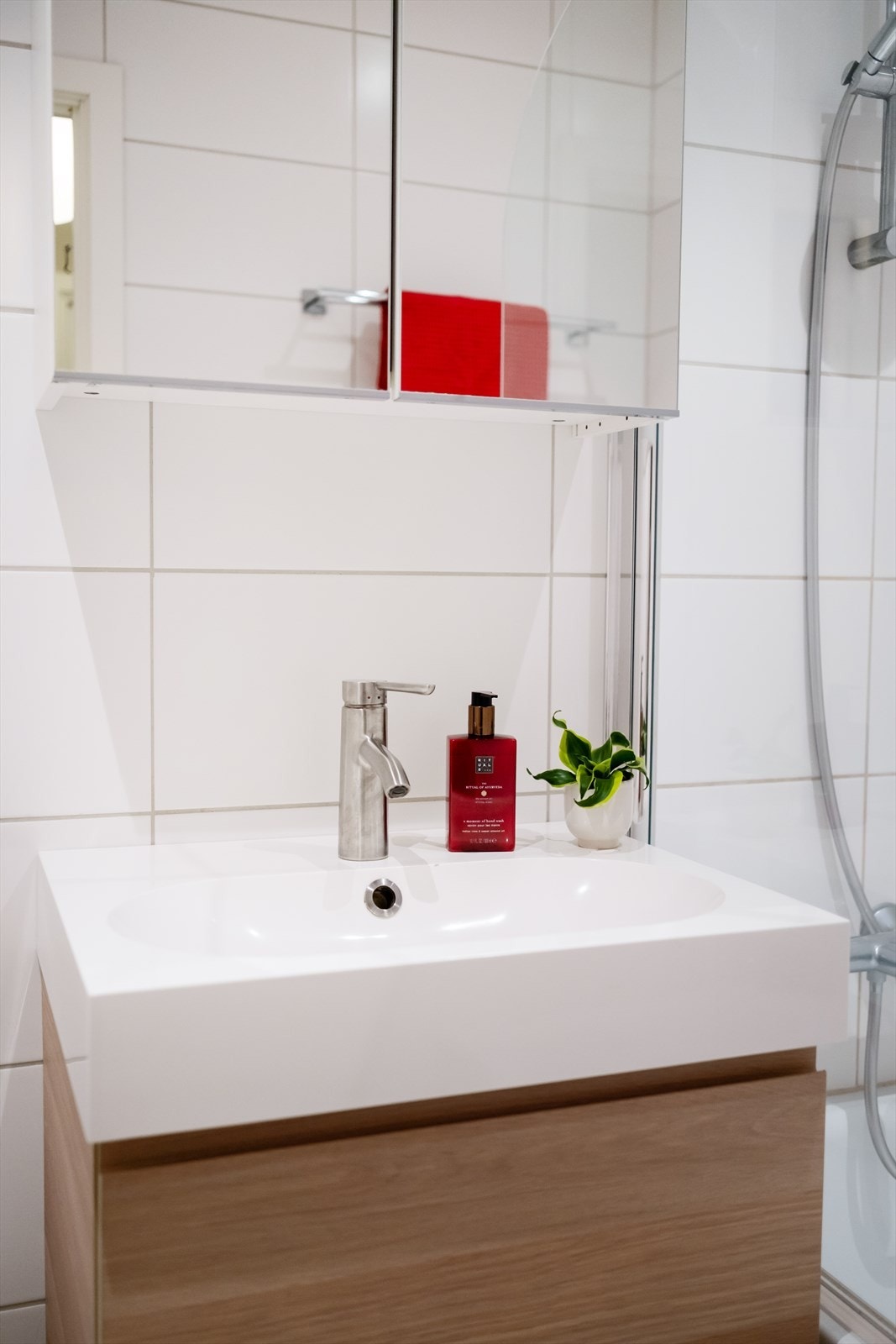 Rommet er innredet med servantskap med ett-greps blandebatteri, vegghengt toalett med innebygd sisterne, speilskap og innmurt badekar med glassvegg. Galleribilde